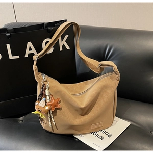 Détail d'un grand sac bandoulière kaki avec étiquette mode et charm ours en peluche