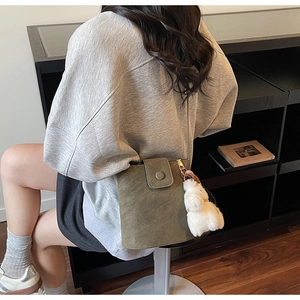Vue détaillée d'un sac seau en daim vert foncé avec un pendentif en peluche blanche