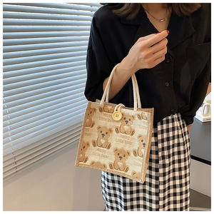 Detail of linen tote bag with cartoon bear print, cotton rope handle and button closure
