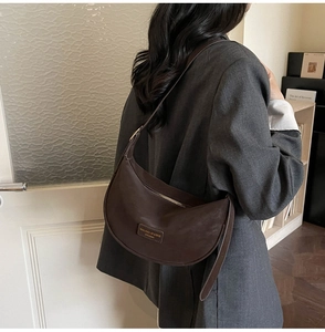 Detail of dark brown dumpling bag with pebbled leather texture and minimalist shoulder strap