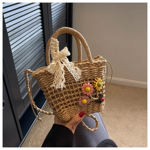 Detailed close-up of woven straw bag with floral accents and delicate lace bow detail