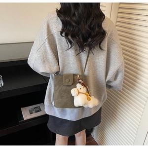 Sac seau en daim vert olive avec charm poney en peluche blanche porté par un mannequin