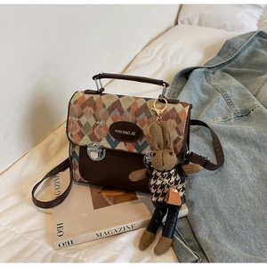 Détail du sac à main en cuir marron matelassé avec motifs colorés et breloque lapin