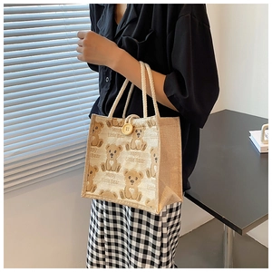 Detailed view of beige linen tote bag with brown bear patterns and cotton rope handle