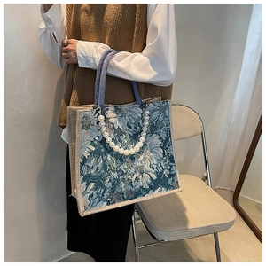 Close-up of vintage floral jacquard tote bag with elegant pearl strap and woven handles