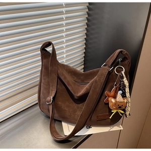 Détail d'un sac hobo en cuir vintage marron foncé avec une texture souple et un écusson