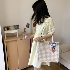 Detail of light yellow summer dress with lace fringe and woven bag with silk scarf accessory