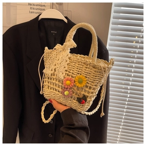 Detailed close-up of straw bucket bag with floral crochet and white lace bow detail