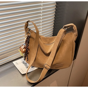 Détail du sac bandoulière en cuir beige avec étiquette mode et charm ours mignon