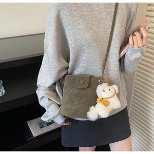 Détail d'un sac bandoulière vintage vert olive avec un joli pendentif agneau en peluche