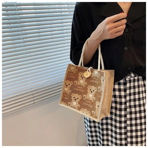Detail of linen tote bag featuring cute cartoon bears and cotton handle with button closure