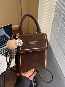 Vertical chocolate brown matte leather tote bag with gold stud trim and plush pendant