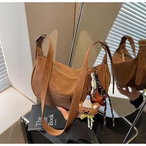 Detail view of brown faux leather hobo bag with teddy bear charm and adjustable strap