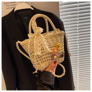 Detailed shot of woven straw bag with 3D fabric flowers, lace bows and a ladybug charm
