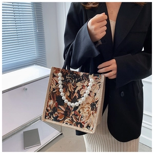 Close-up of floral jacquard tote bag with decorative pearl handle and woven strap