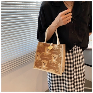 Close-up of linen tote bag with cartoon bear print and wooden button closure
