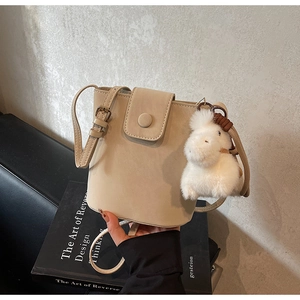 Détail du sac seau beige avec boucle métallique et joli accessoire en peluche animale