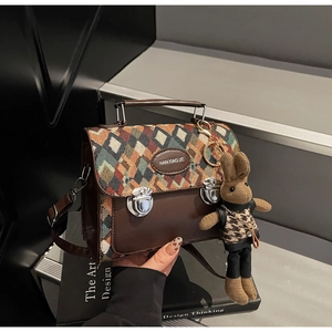 Détail d'un sac bandoulière matelassé avec base en cuir marron et pendentif lapin mignon