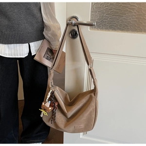 Détail du sac hobo kaki avec breloque ours, glands et étiquette Fashion sur porte