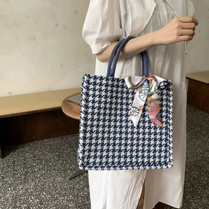 Detail of blue houndstooth tote bag with silk scarf on handle and textured fabric