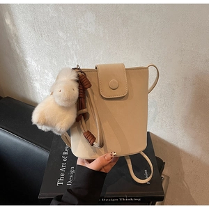 Détail du sac seau beige avec charmant lapin en peluche et bandoulière à nœud tissé
