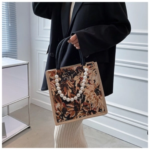 Detail of floral tapestry tote bag featuring luxury pearl chain and woven rope handle