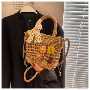 Detail of woven straw bag with floral decorations and a white lace bow accent