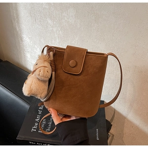 Détail du sac seau marron en daim avec fermoir magnétique et pendentif petit cheval