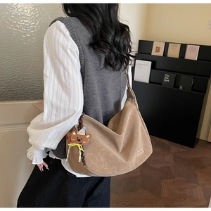 Détail du sac demi-lune en daim avec un adorable pendentif ours sur la bandoulière
