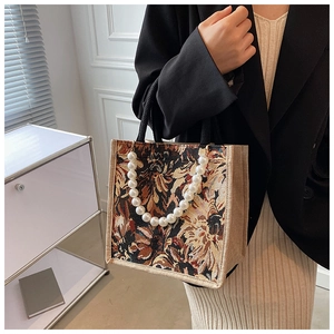 Detail of floral jacquard tote bag featuring pearl bead handle and woven circular grip