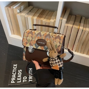 Détail du sac à motif losange avec boucle en métal et breloque lapin sur bureau
