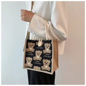 Detail of linen tote bag featuring cartoon bear print and decorative wooden button closure