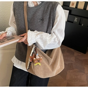 Détail du sac demi-lune kaki avec charm d'ours et foulard à carreaux style vintage