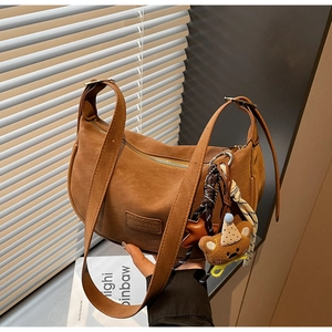 Caramel crescent shoulder bag with smooth texture and cute bear plush charm detail