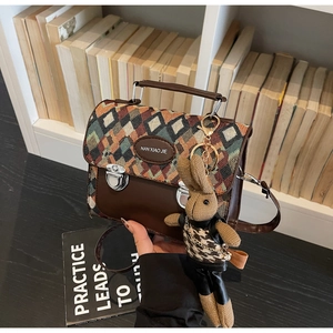 Détail du sac tissé matelassé avec garniture en cuir brun, fermoir métal et charme lapin