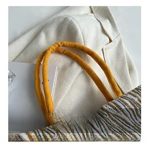 Detail of woven tote bag with yellow rope handles and striped textured fabric