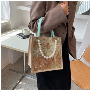 Detailed shot of floral tote bag featuring elegant pearl handle and mint green strap