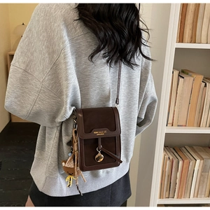 Detail of coffee PU leather mini crossbody bag with a cute bear plush keychain