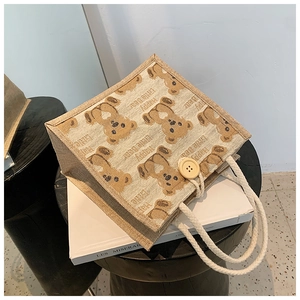 Détail du sac repas en lin avec motif ours, poignées en corde et bouton en bois