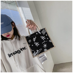 Detail of canvas tote bag with black and white graffiti print and cotton rope handles