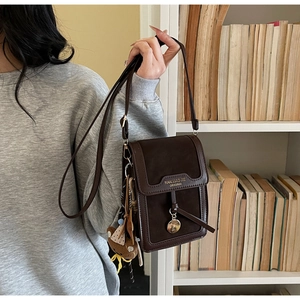 Detail of dark brown vintage flap bag with metal ring charm and cute bear keychain