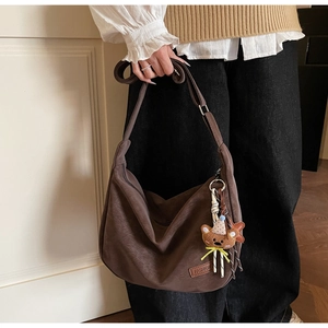 Sac hobo en cuir marron avec étiquette mode et breloque ours porté par un mannequin