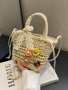 Handmade woven straw bucket bag with floral accents and white lace bow detail