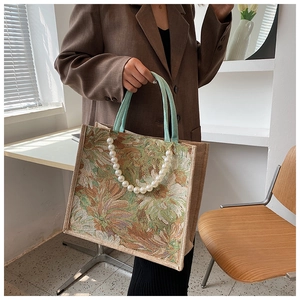 Detail of vintage floral tote bag with pearl chain and mint green handles in chic interior