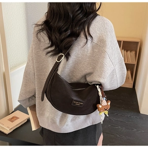 Close-up of brown crescent crossbody bag with adjustable strap and cute bear charm