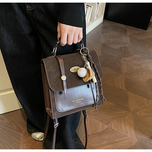 Detail van donkerbruine vintage handtas met gespen en een baseball sleutelhanger