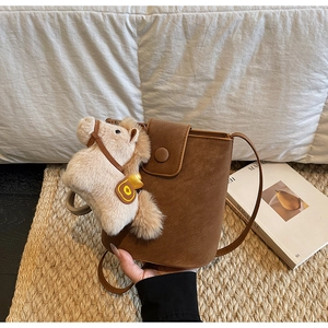 Détail du sac seau marron en cuir grainé litchi avec une breloque poney en peluche