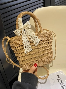 Handwoven straw tote bag featuring a large white lace bow in a natural tan color