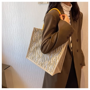 Detail of linen tote bag featuring yellow wave patterns and braided rope handles