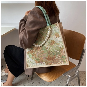 Detail of floral tote bag with vintage sunflower pattern and elegant pearl strap